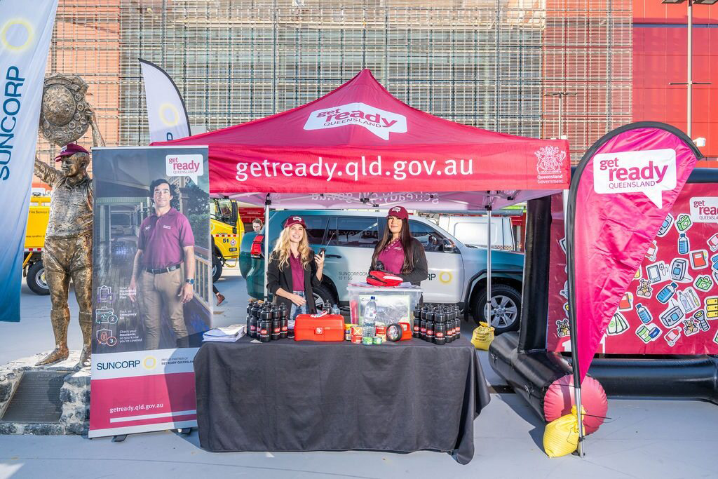 Two people stand at a Get Ready Queensland booth outside Suncorp Stadium.