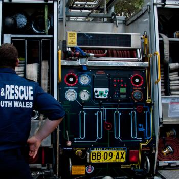 A NSW Fire and Rescue employee stands behind a fire truck.