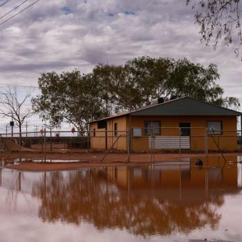 A house surrounded by low levels of brown water.