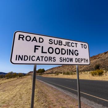 A sign reads "Road subject to flooding. Indicators show depth".