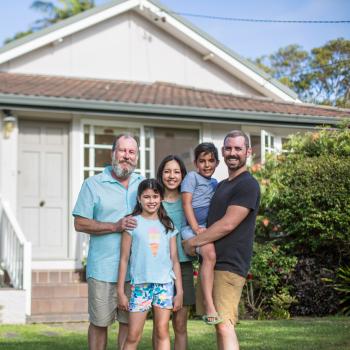 A family stand outside a home.