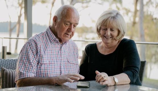 An elderly couple inspect a mobile phone