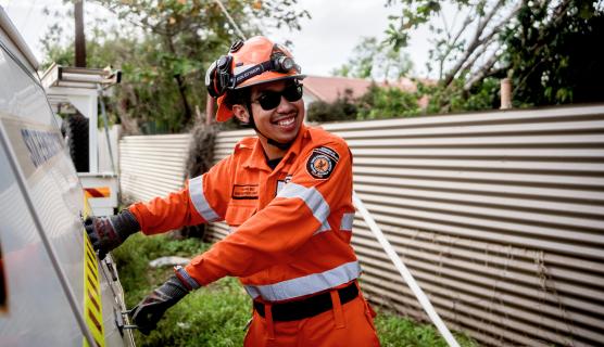 A person in an SES uniform and protective helmet works on a residential property.