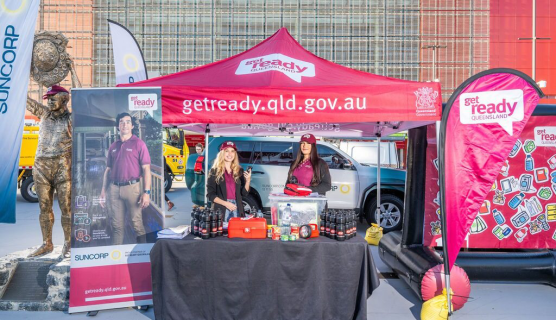 Two people stand at a Get Ready Queensland booth outside Suncorp Stadium.