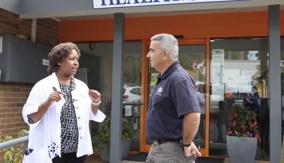 A NEMA employee and a community member speak outside a health centre.