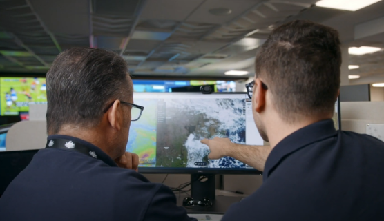 Two NEMA employees use a computer to assess satellite imagery in the National Situation Room.