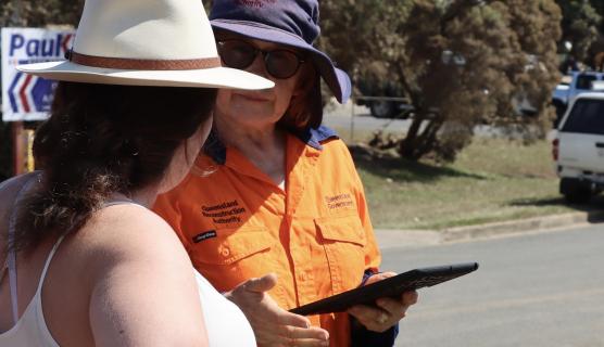 A Queensland Reconstruction Authority staff members talks to a community member.