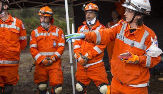 A team of four people wearing protective equipment having a discussion under a large marquee.