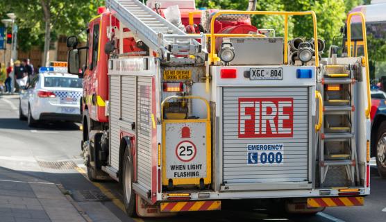 The rear view of a fire truck and police car on a city street.