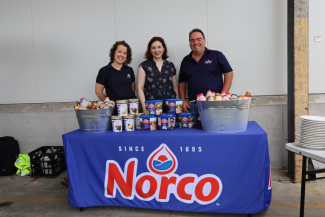 A photo of Norco staff standing behind a table covered with dairy produce