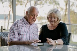 An elderly couple inspect a mobile phone