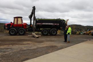 A photo of an earthmover watched by two people.