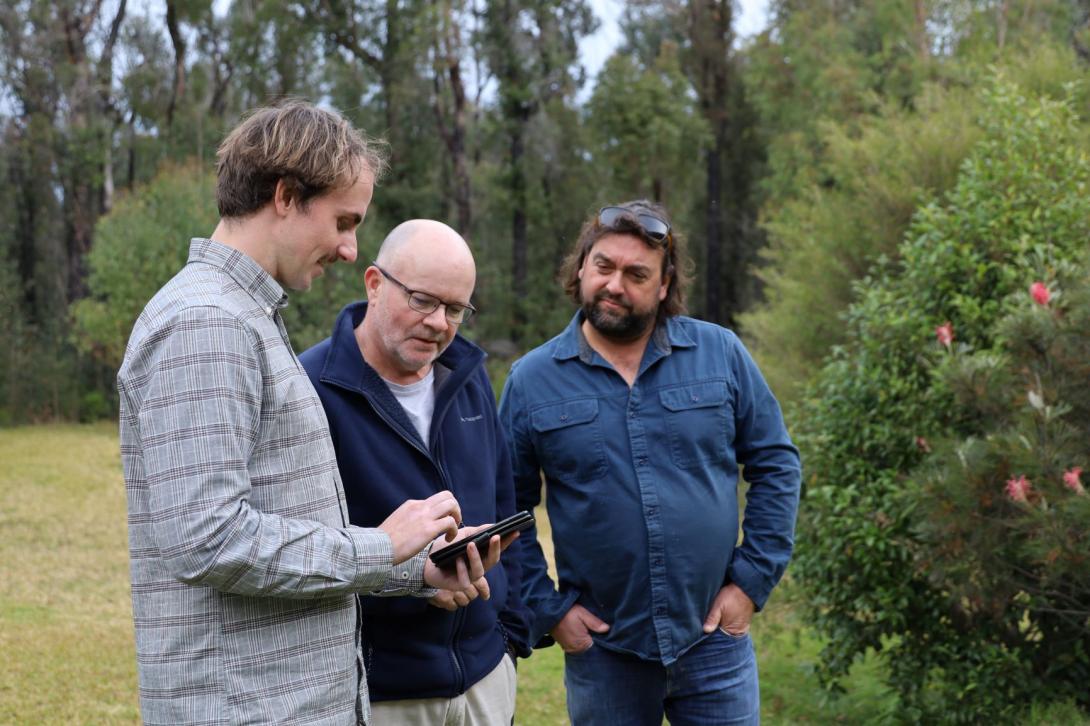 Three people looking at phone in Little Forest NSW