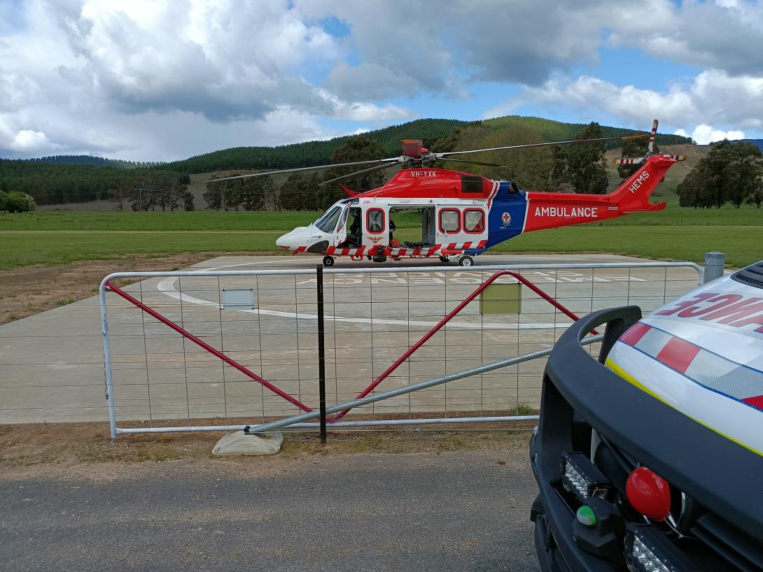 concrete helipad behind a fence in foreground with red and white helicopter in background